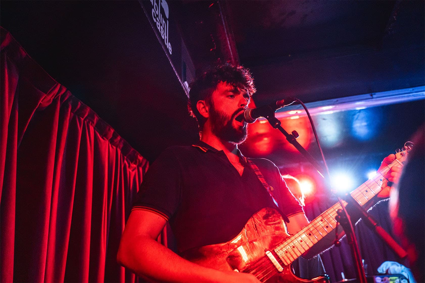 Guitarist singing under red and blue light